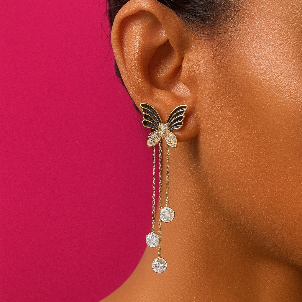 Elegant black butterfly earrings with cascading crystal chains, modeled on a vibrant pink background