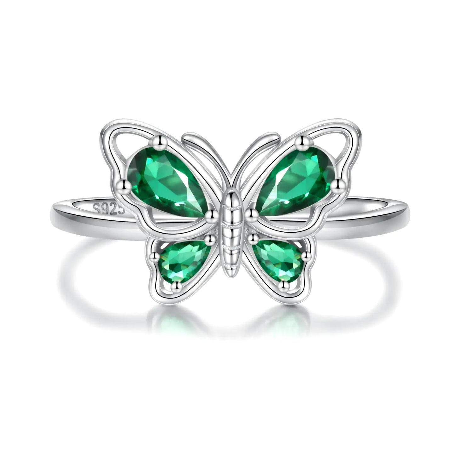 Butterfly-shaped ring with green gemstones on a white background “Close-up of a silver butterfly-shaped ring with green gemstone wings on a white background”