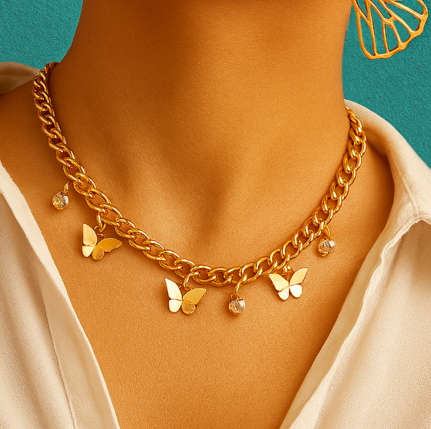 Bold gold chain necklace with butterfly pendants and crystal charms, worn with a beige top on teal background