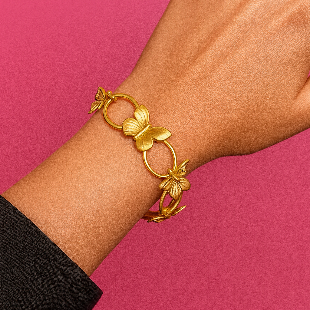Gold bracelet with floral designs on a wrist against a pink background “Gold floral butterfly bracelet on wrist with a vibrant pink background”
