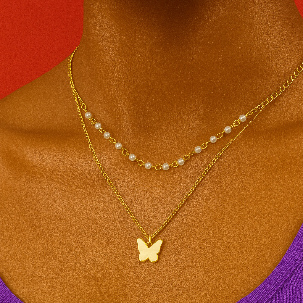 Gold necklace with a butterfly pendant on a person wearing a purple top against a red background "Layered gold necklace with a butterfly charm and pearl chain on a woman wearing a purple top and red background"
