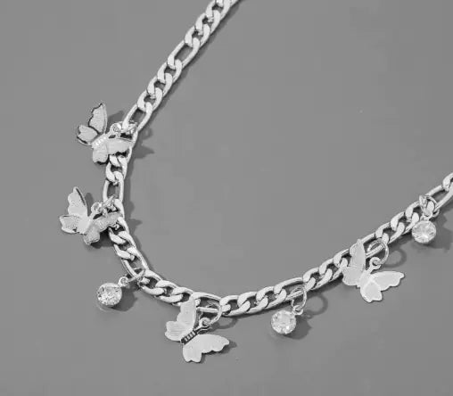 “Delicate silver chain necklace with butterfly and crystal charms on a neutral gray background”
