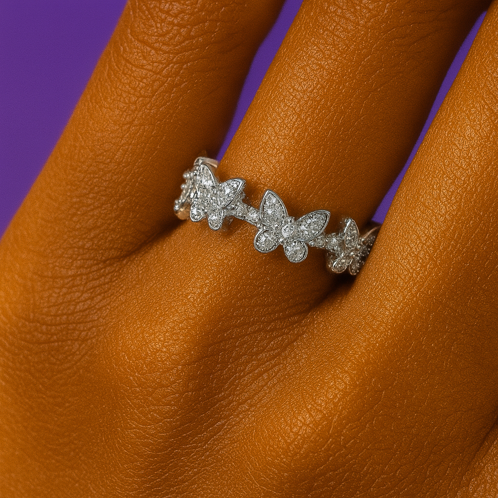 Silver butterfly-shaped ring on a person's finger with a purple background “Elegant silver ring with butterfly-shaped crystals worn on a hand against a purple background”
