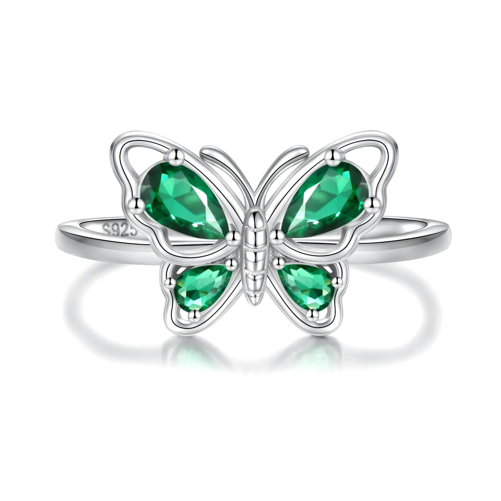 Butterfly-shaped ring with green gemstones on a white background “Close-up of a silver butterfly-shaped ring with green gemstone wings on a white background”
